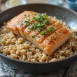 A delicious, perfectly cooked salmon brown rice garnished with fresh herbs, served over a bed of in a rustic bowl.